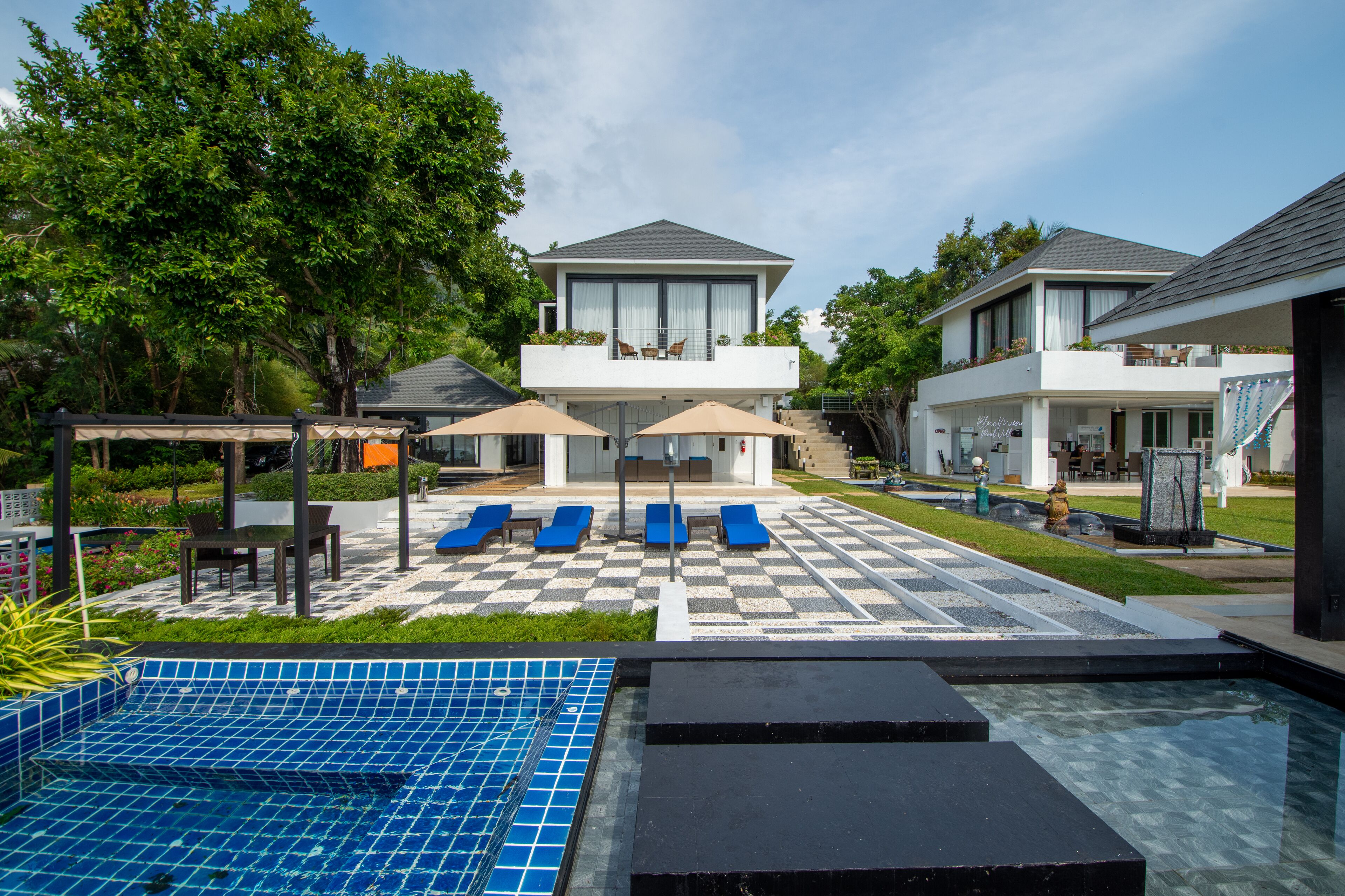 Una casa moderna de dos pisos con piscina, mobiliario exterior y un jardín bien cuidado.