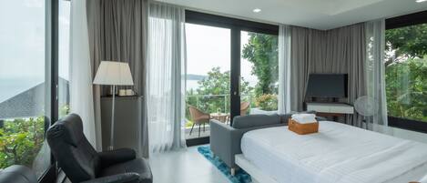 A modern hotel room with a large bed, a desk, a chair, and a TV.