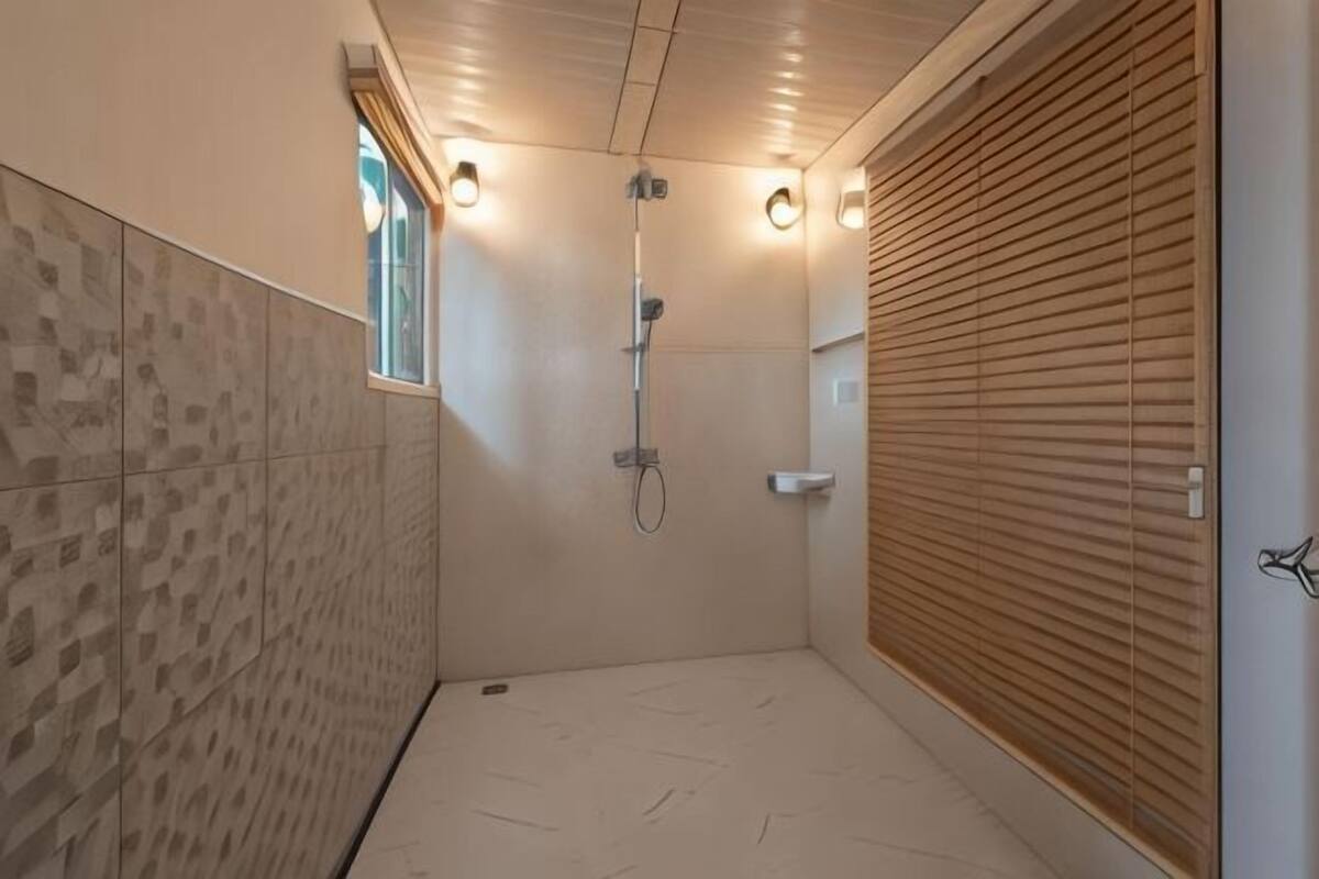 A shower with a wooden door, a window, and a tiled wall.