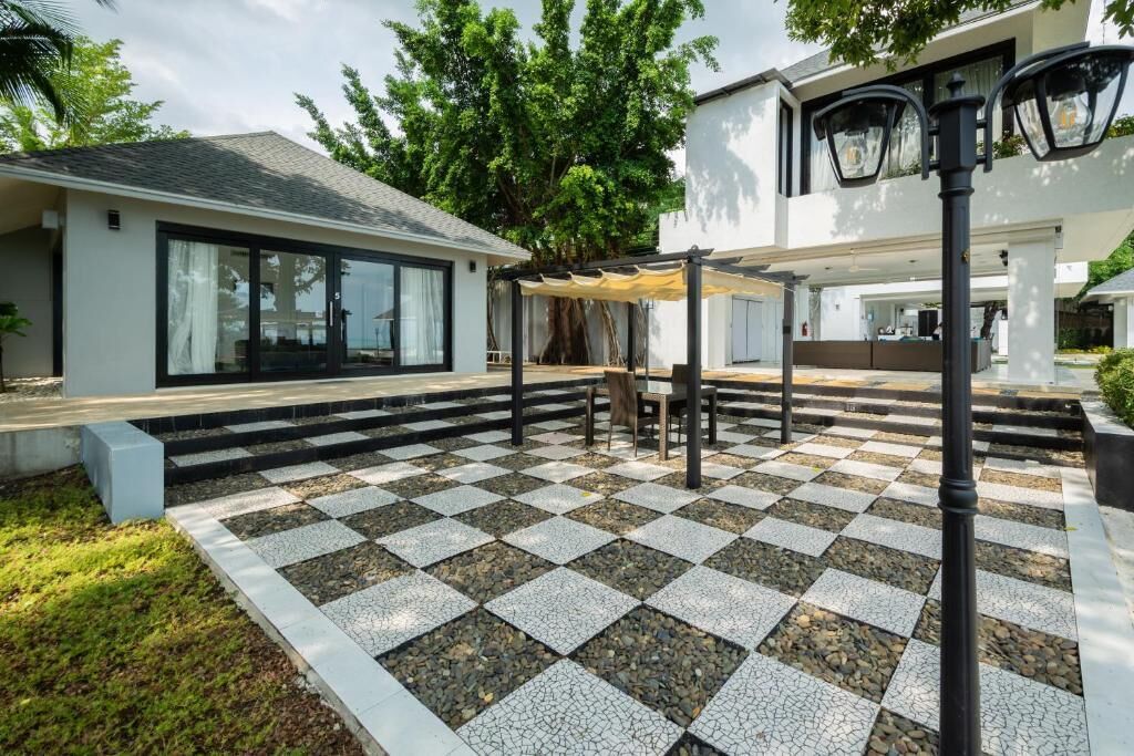 Een modern buiten terras met een zwart-wit schachthoogtepatroon, een pergola en een lantaarn.