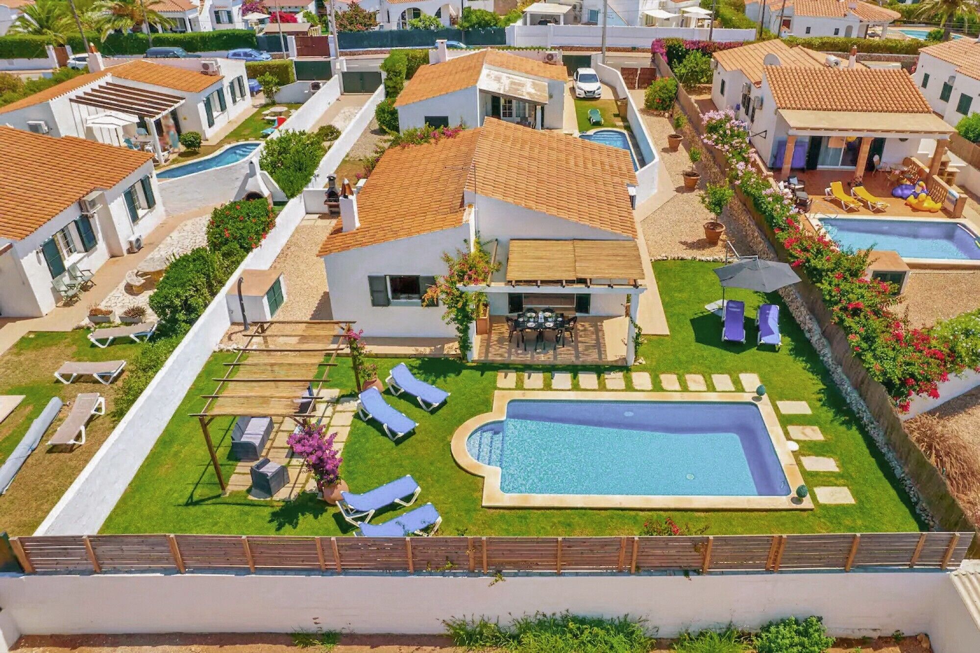 Zona residencial con casas, piscina y espacios exteriores con mobiliario.