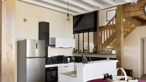 A compact kitchen with a refrigerator, microwave, oven, and white cabinetry.