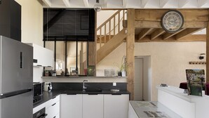 A modern kitchen with a central island, built-in appliances, and a wooden staircase.