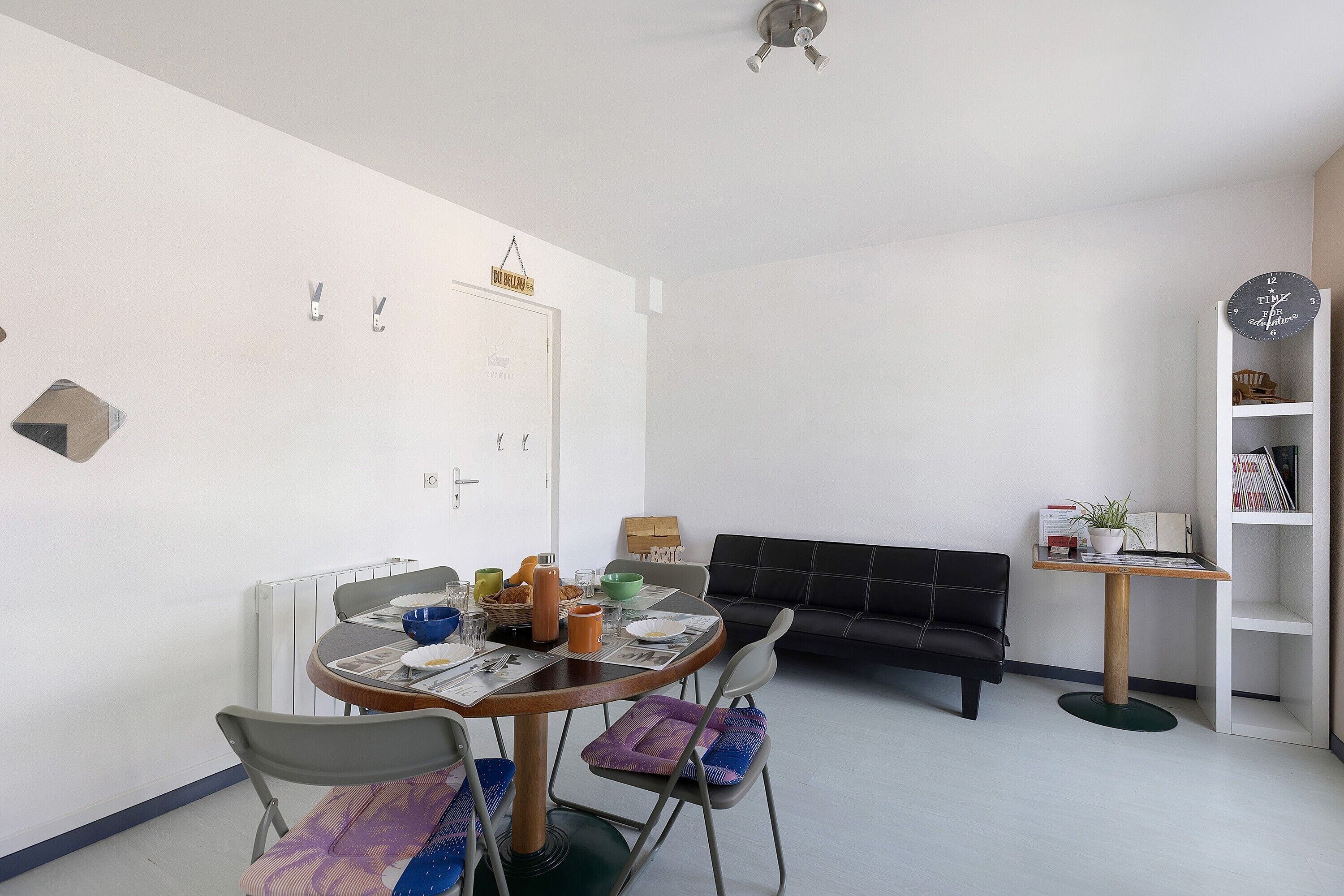 Un coin repas avec une table ronde, des chaises et un canapé noir.