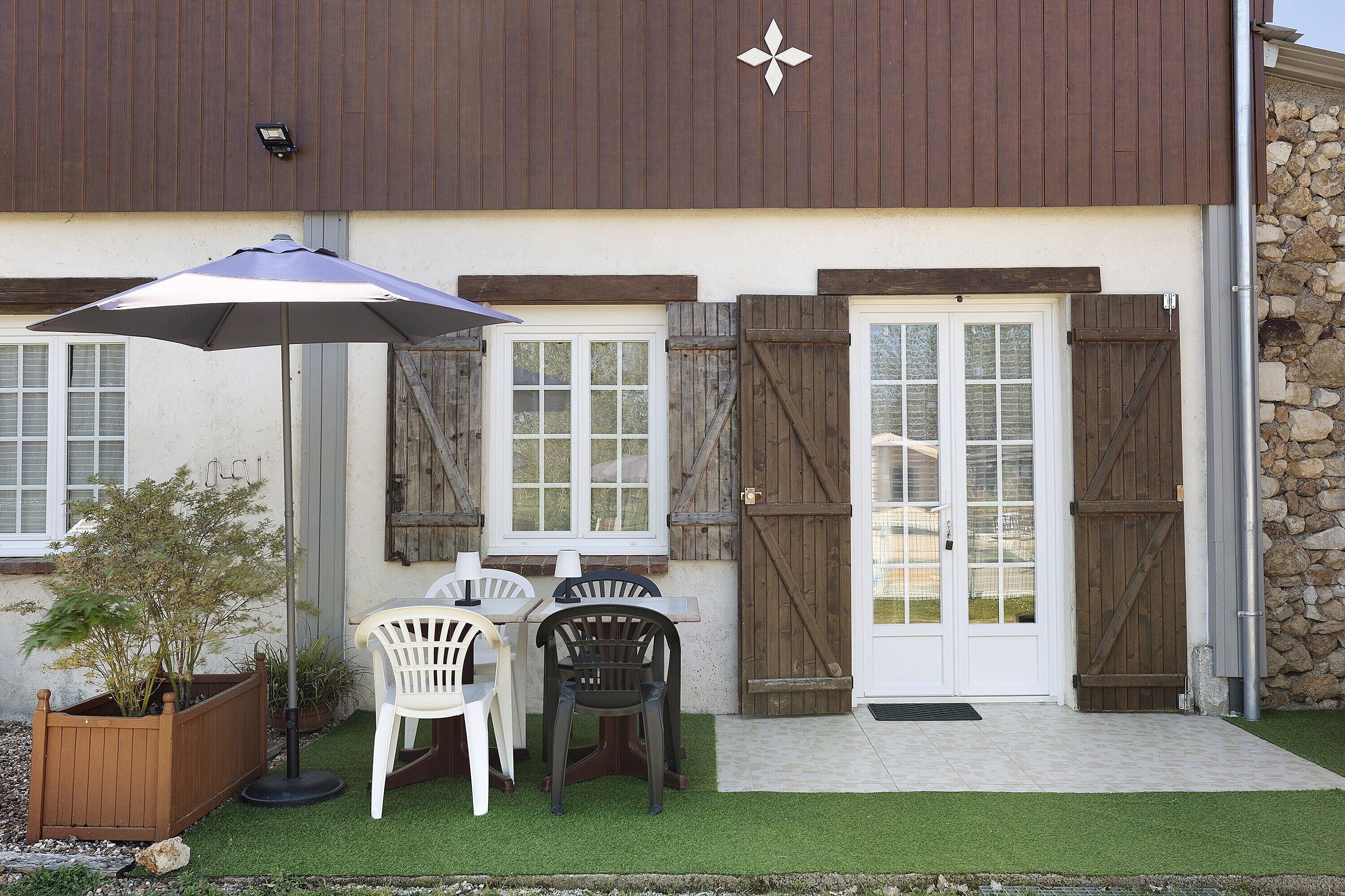 Un bâtiment avec une porte en bois, une porte blanche et une fenêtre.