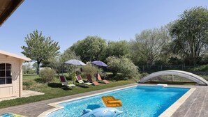 A swimming pool with a dolphin float, lounge chairs, and umbrellas.