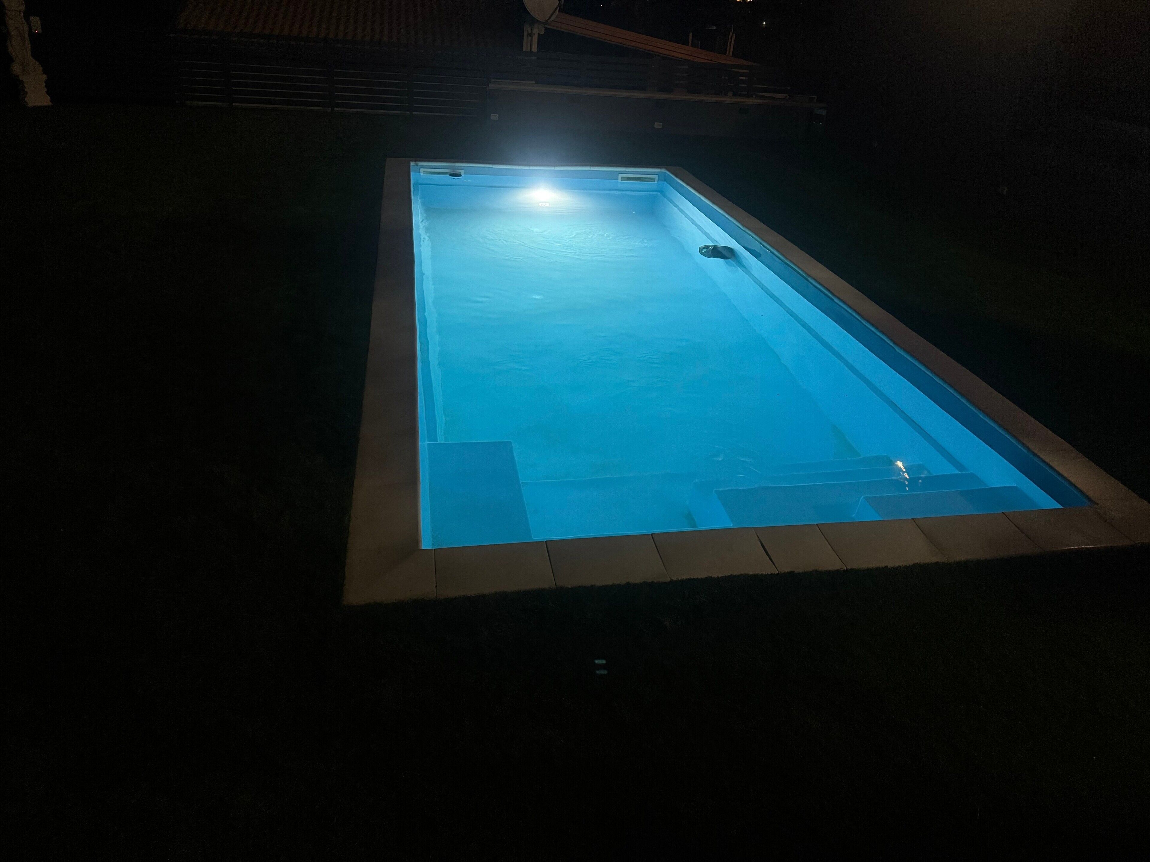 A rectangular swimming pool with a light source at the far end.