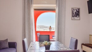 Un comedor con mesa, sillas y vista a un balcón exterior a través de un arco.