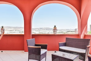 Un balcón con mobiliario de mimbre y vistas a un paisaje desértico.