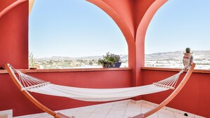 Una hamaca en una habitación con paredes rojas y vista a un paisaje desértico.