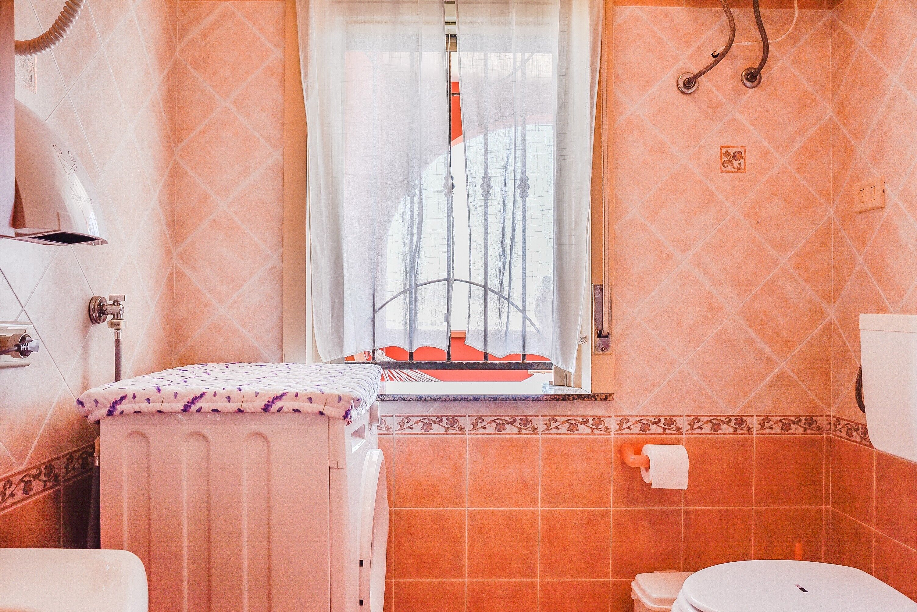 A bathroom with a window, a radiator, a toilet, and a sink.