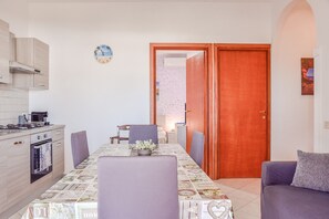Un comedor con una mesa y sillas, una cocina con estufa, y una puerta que da a otra habitación.