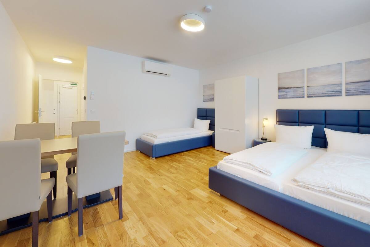Une chambre d’hôtel avec un grand lit, un lit plus petit, un bureau avec des chaises et une armoire.