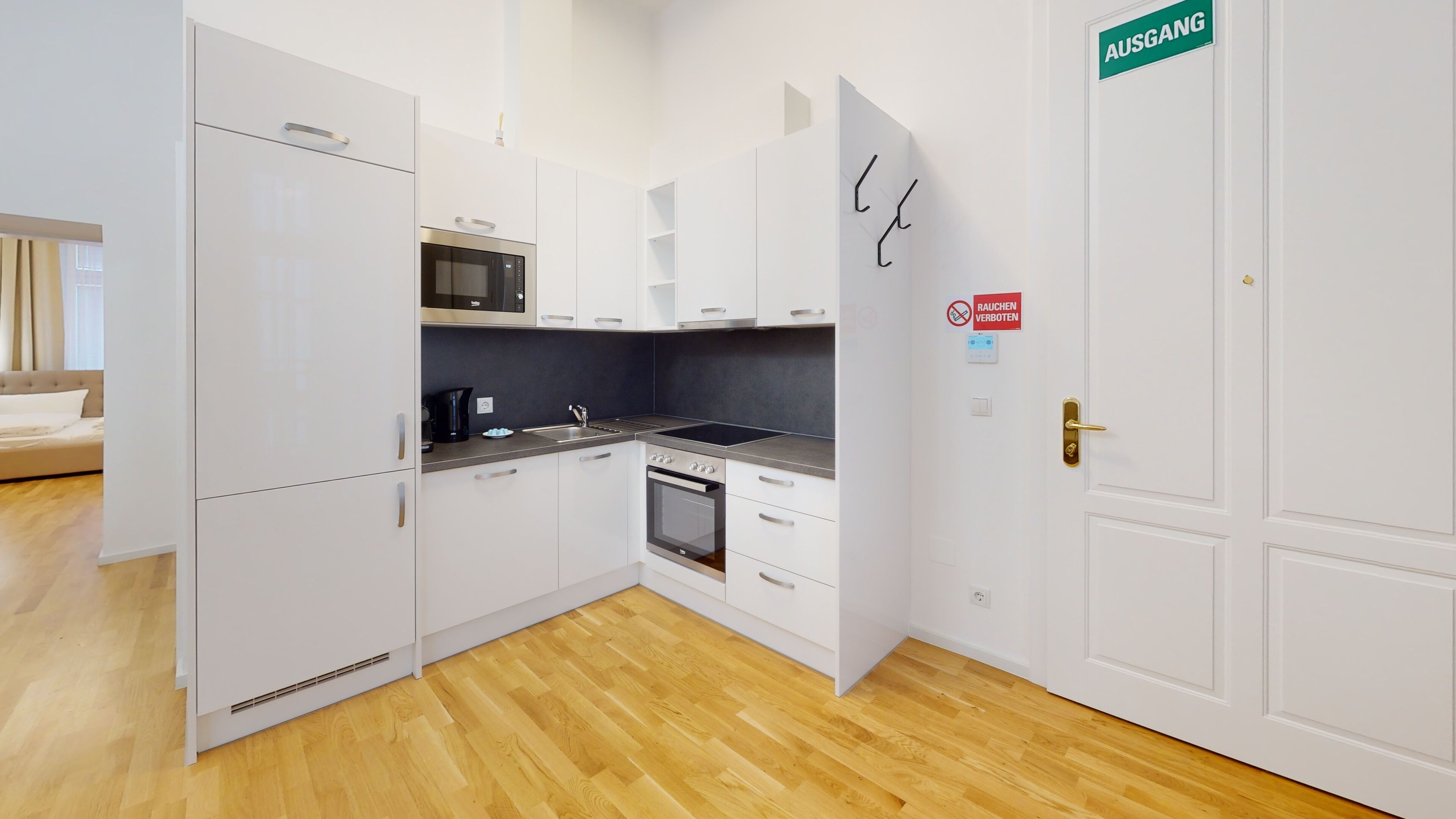 Una cocina moderna con armarios blancos, microondas, estufa y un lavamanos. Hay un cartel en la puerta que dice 