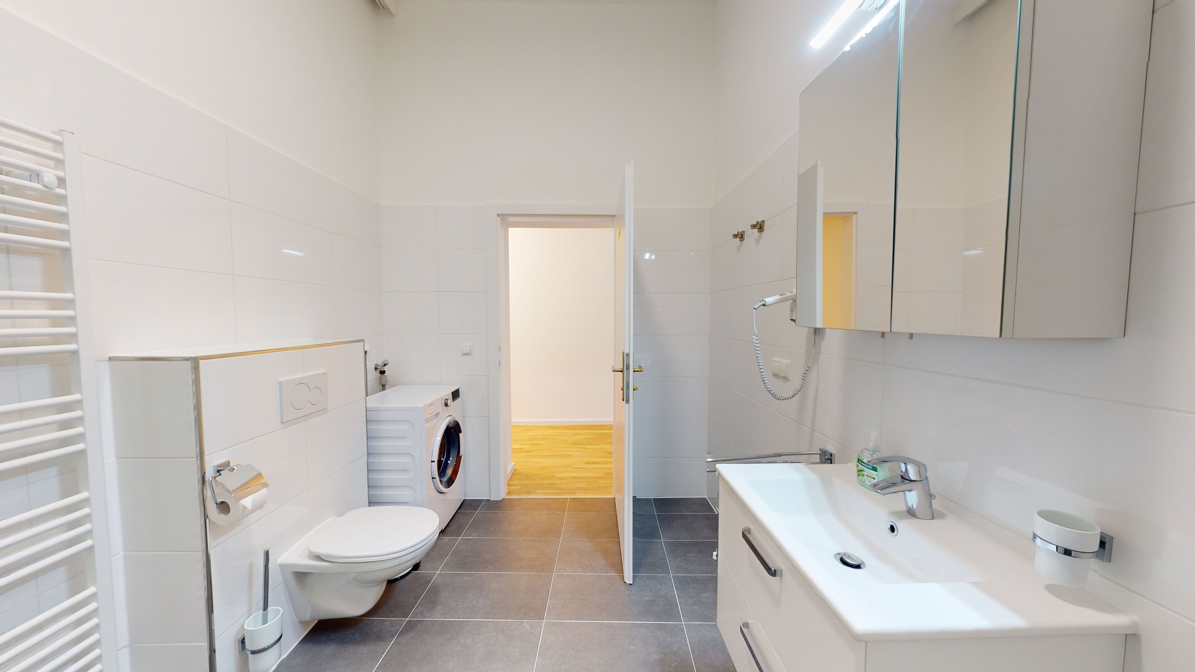 A modern bathroom with a toilet, washing machine, and sink.