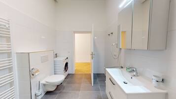 A modern bathroom with a toilet, washing machine, and sink.