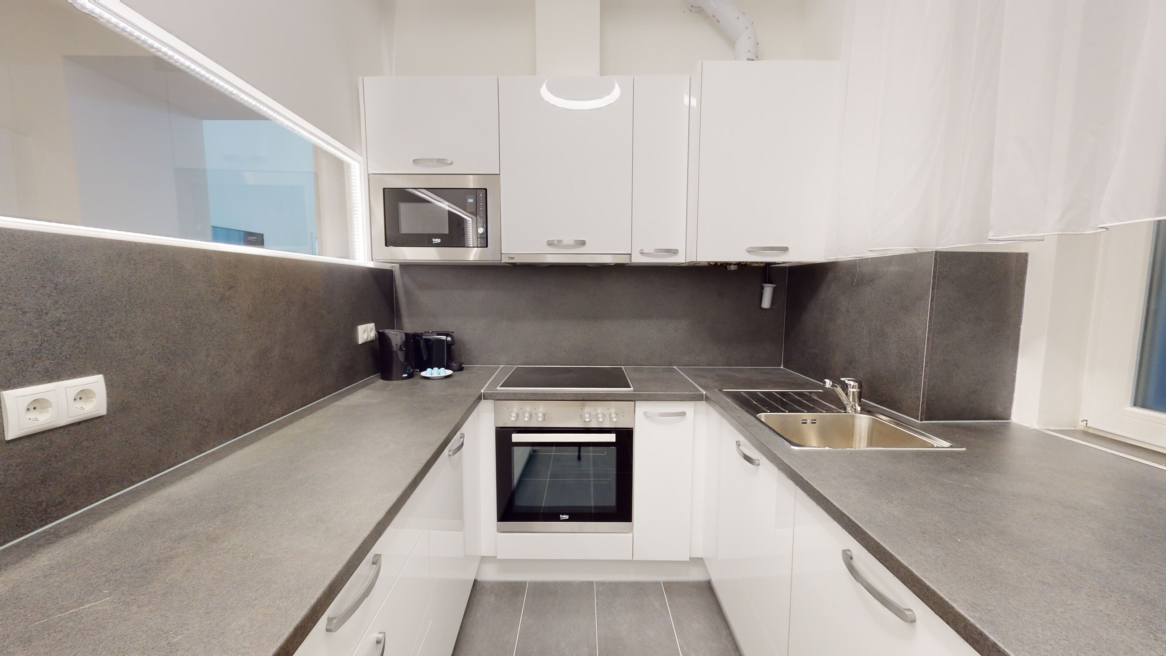 A compact kitchen with a built-in oven, a microwave, and a sink.