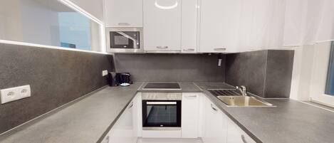 A compact kitchen with a built-in oven, a microwave, and a sink.