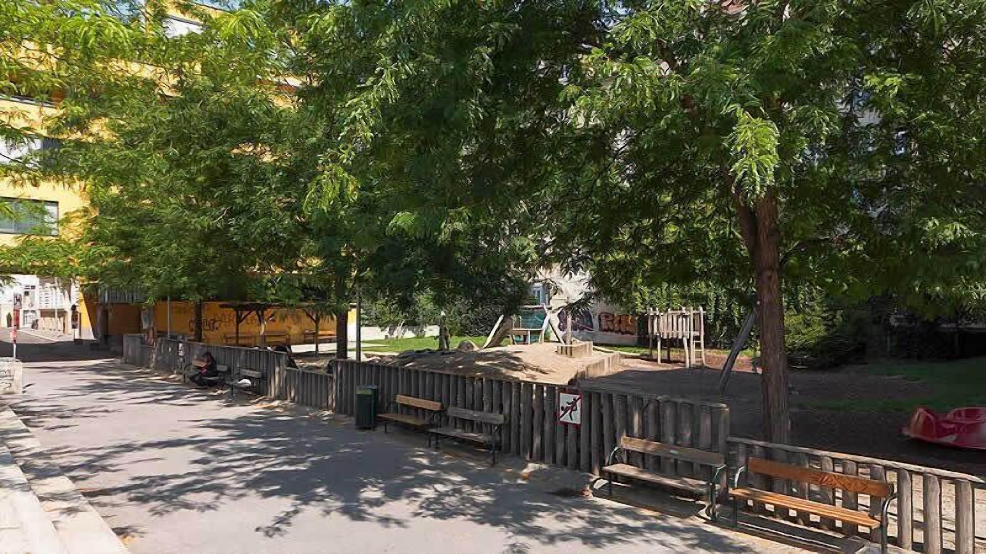 Um parque com bancos, parquinho infantil e área cercada.