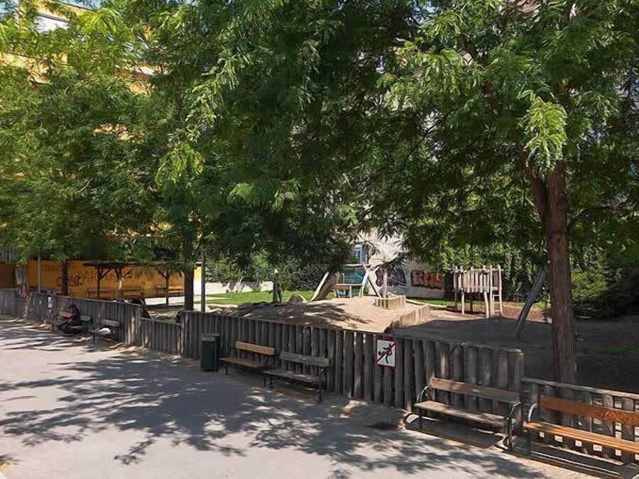 Um parque com bancos, parquinho infantil e área cercada.