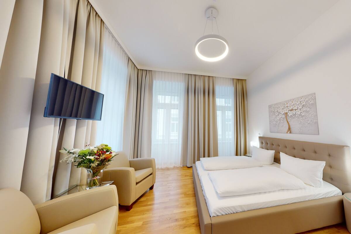Une chambre d’hôtel moderne dotée d’un grand lit, d’un téléviseur à écran plat, d’un canapé et d’une table à manger.