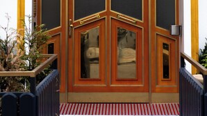 L’entrée d’un hôtel, avec une grande porte richement décorée et portant le numéro 16.