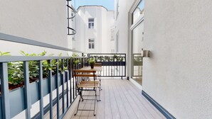 Un étroit couloir extérieur avec un banc en bois et des plantes en pot.