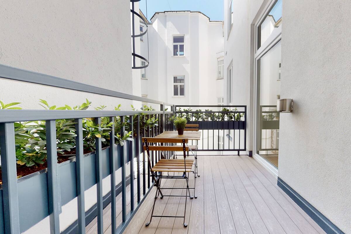 Un étroit couloir extérieur avec un banc en bois et des plantes en pot.
