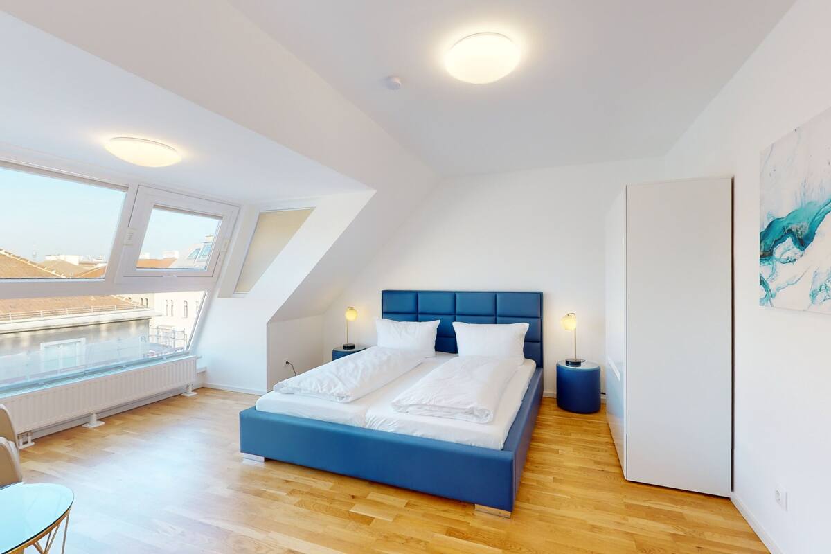 Une chambre moderne avec un grand lit, des fenêtres de toit et une vue sur la ville.