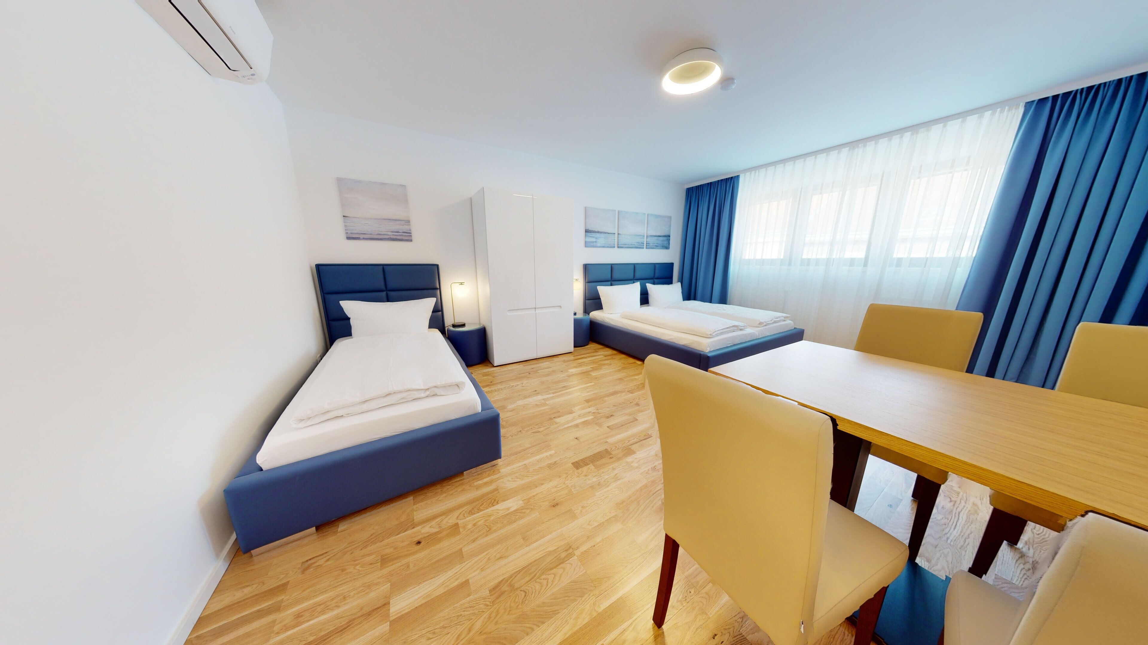 A hotel room with two beds, a dining table, and chairs.