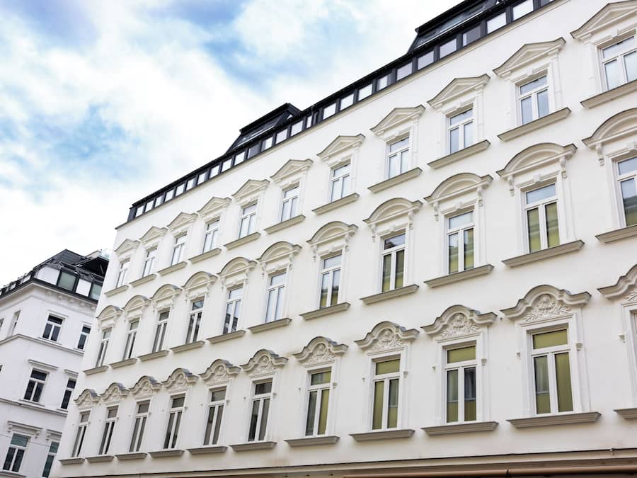 A multi-story building with white facades and green window frames.