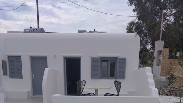 Un edificio blanco con piscina, mobiliario exterior y una pared de piedra.