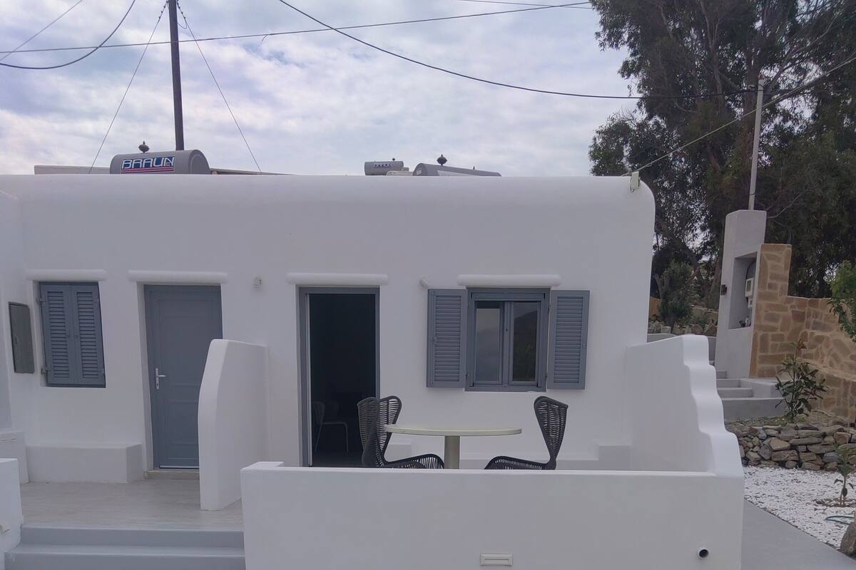 Un edificio blanco con piscina, mobiliario exterior y una pared de piedra.