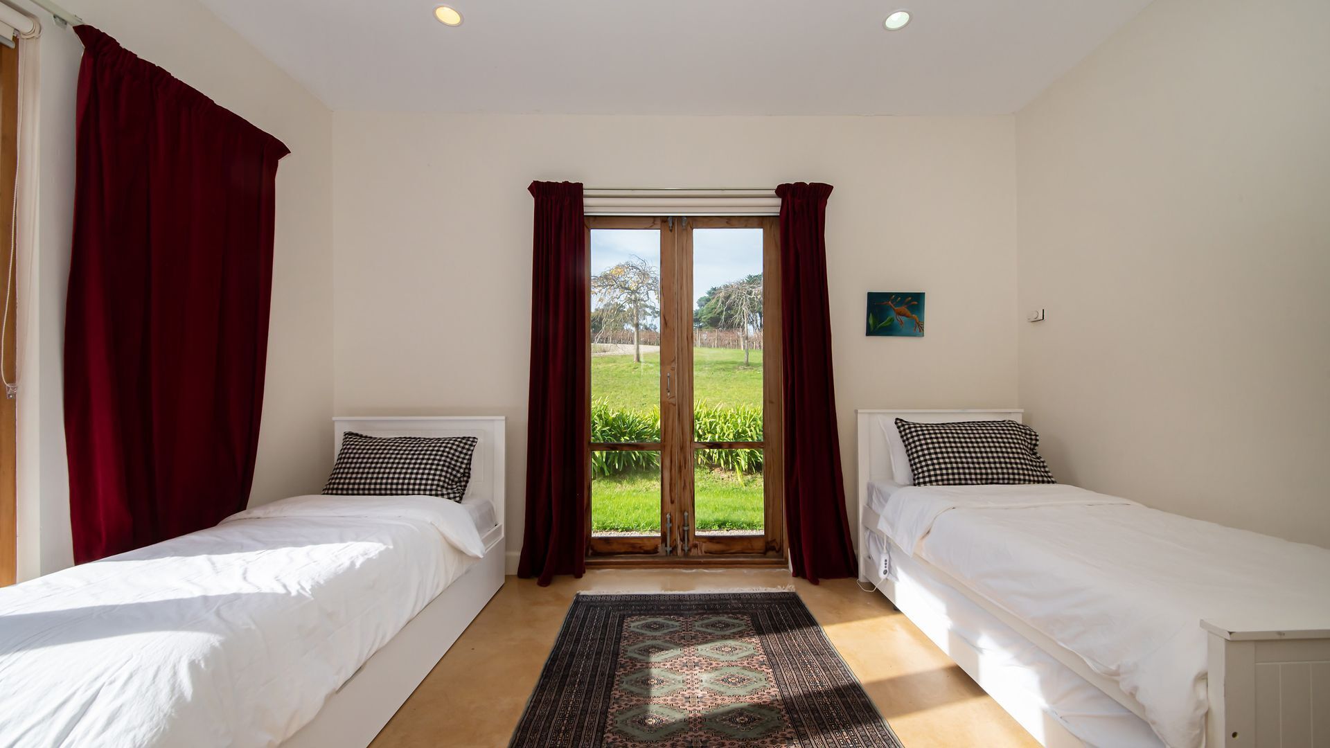 Une chambre avec deux lits simples, une grande porte-fenêtre coulissante donnant sur un balcon et une vue sur la verdure environnante.