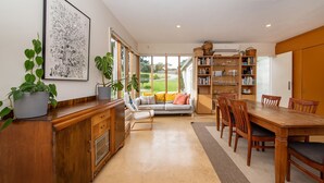 A spacious kitchen with a dining area, wooden cabinets, and a large window overlooking a garden.