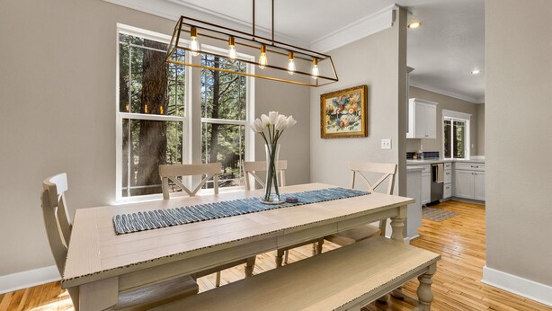 A dining area with a wooden table, benches, and a modern pendant light. - Modern Cabin Minutes to Flagstaff! Trailside Retreat w/ Trails/Park & 2 Car Garage (Flagstaff)