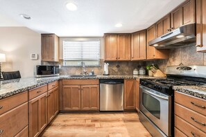 A kitchen with wooden cabinets, a stainless steel dishwasher, a gas stove, and a microwave.
