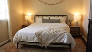 A neatly arranged bedroom with a bed, bedside lamps, a small plant, and a decorative garland on the wall. - Brand new floors in sunny Las Vegas! (Las Vegas)