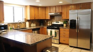 A kitchen with wooden cabinets, granite countertops, stainless steel appliances, and a window with blinds. - Brand new floors in sunny Las Vegas! (Las Vegas)