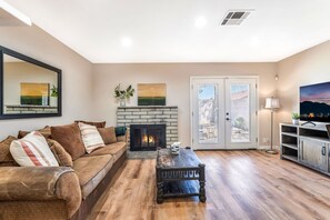 Un salon avec une cheminée, un canapé, une table basse et un téléviseur.