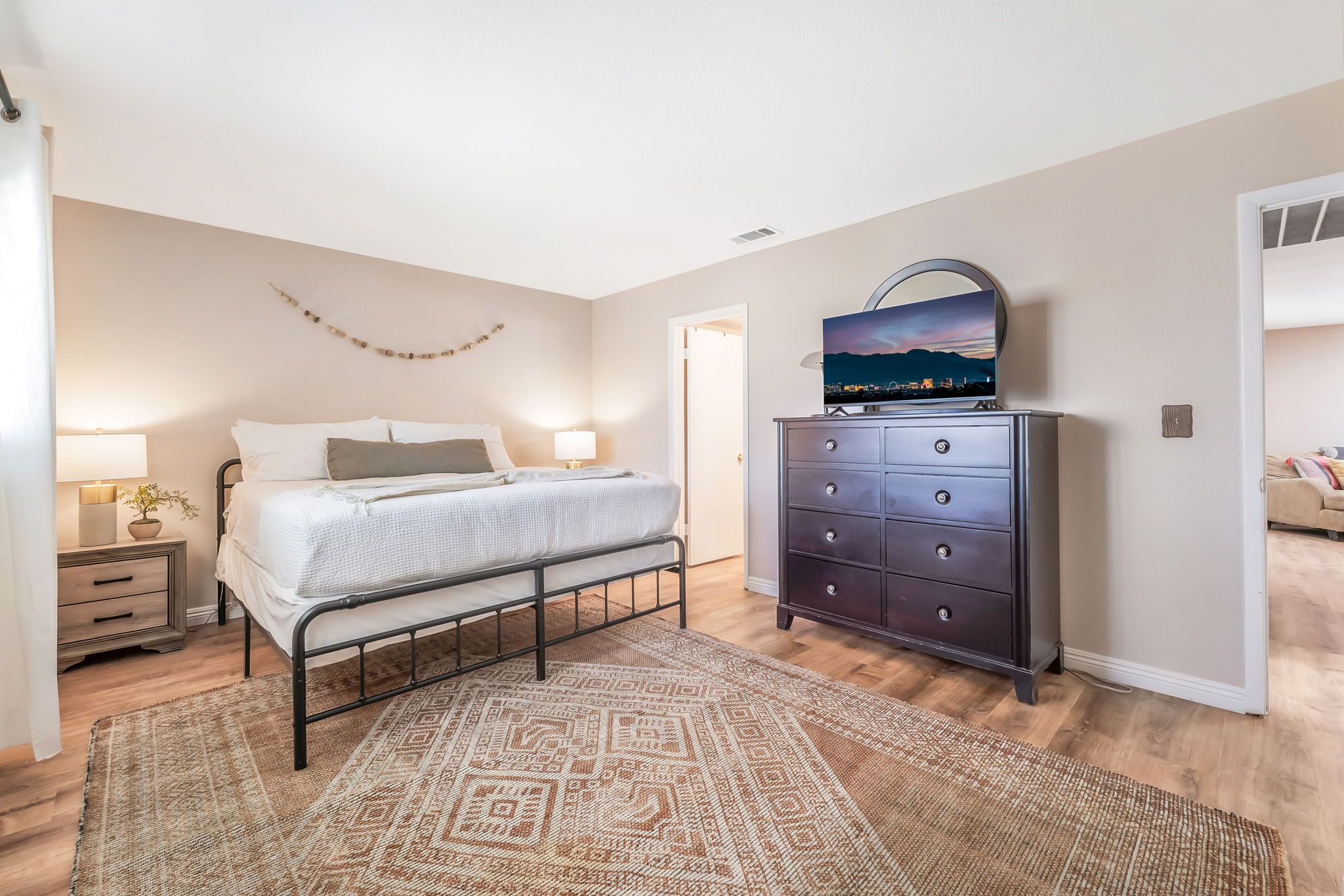 A bedroom with a bed, dresser, and a nightstand with a lamp.