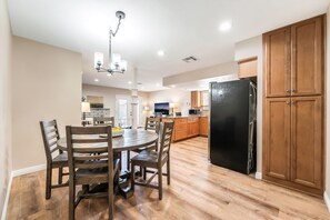 A modern kitchen with wooden cabinets, a black refrigerator, and a dining area with a round table and chairs.