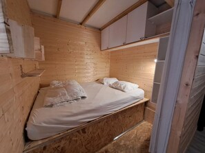 A wooden cabin room with a bunk bed, a shelf with towels, and a small cabinet. - Cozy studio with south balcony, pets allowed, near slopes (Les Deux Alpes)