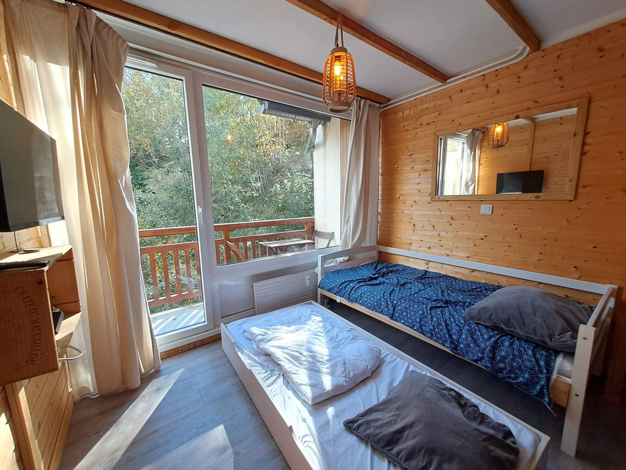 A cabin with a single bed, a small table, a chair, and a wooden deck.