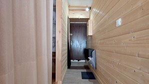Un couloir étroit aux murs en bois, avec une porte en bois au bout.