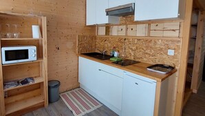Une cuisine de taille réduite, équipée d’un four à micro-ondes, d’un évier et de meubles blancs.