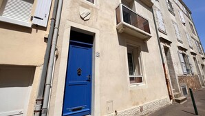 Un edificio con puerta azul, paredes color beige y varias ventanas con contraventanas.