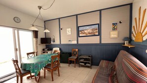 Un área de comedor con una mesa y sillas, un sofá, un televisor y un reloj en la pared.