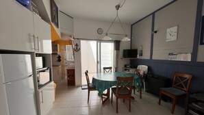 Cocina compacta con comedor, que incluye refrigerador, horno y una mesa con sillas.