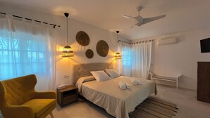 Un dormitorio moderno con cama, mesitas de noche, una silla y un ventilador de techo.
